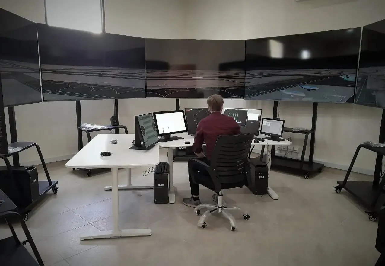 Air traffic control simulator room with a wraparound visual display and controller desks